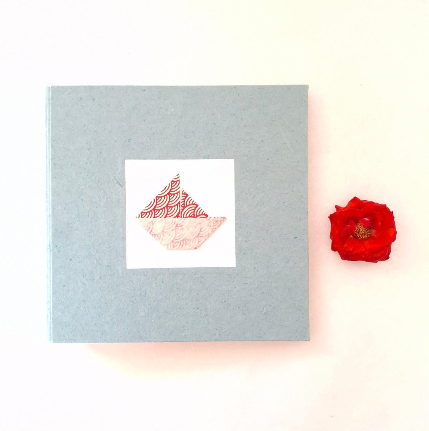 Album nascita con barca origami in rosso, celeste e miele