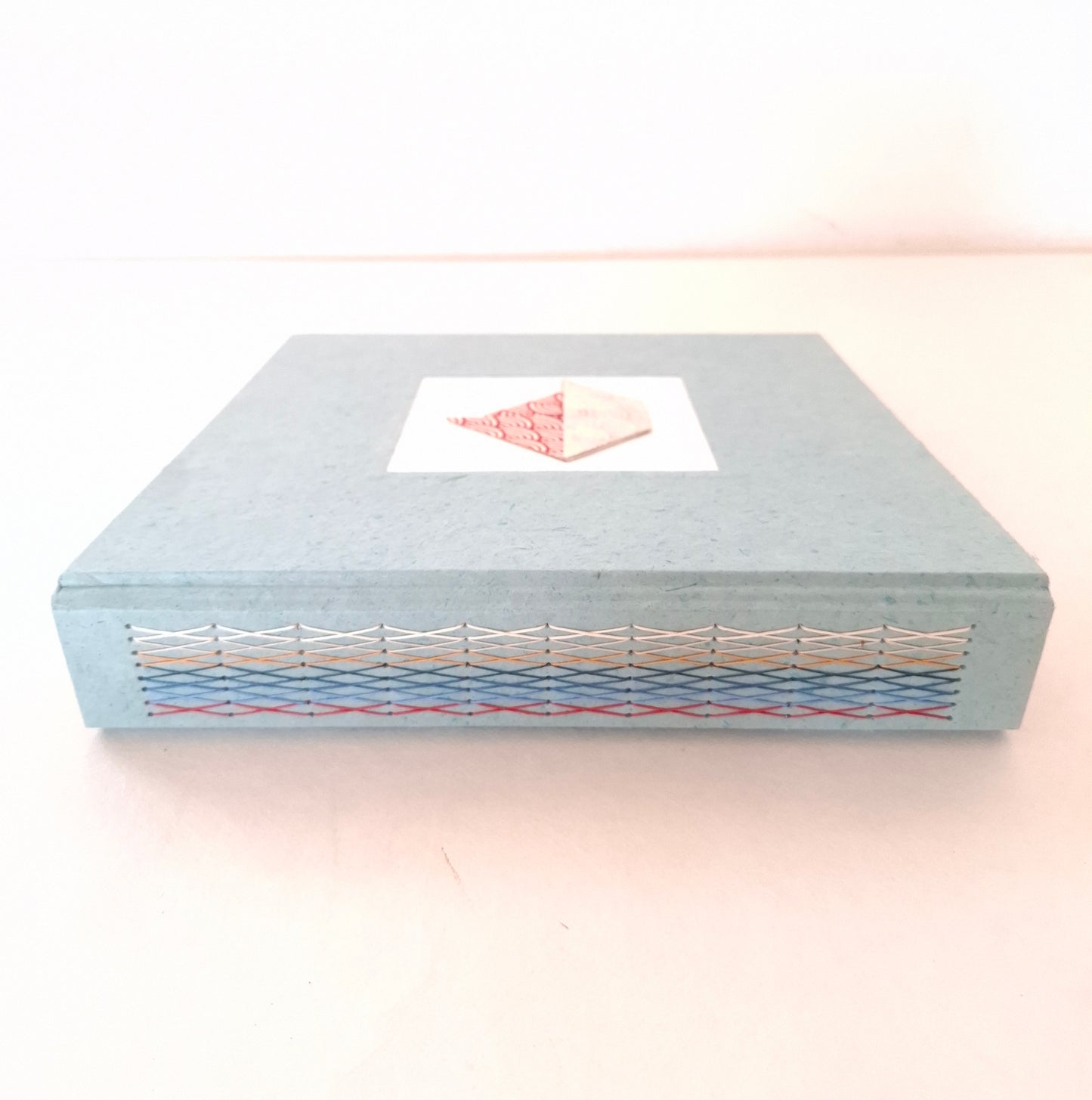 Album nascita con barca origami in rosso, celeste e miele