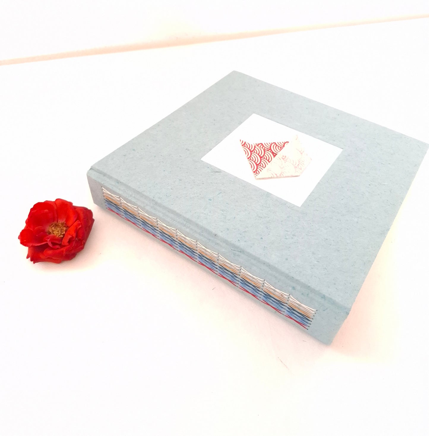 Album nascita con barca origami in rosso, celeste e miele